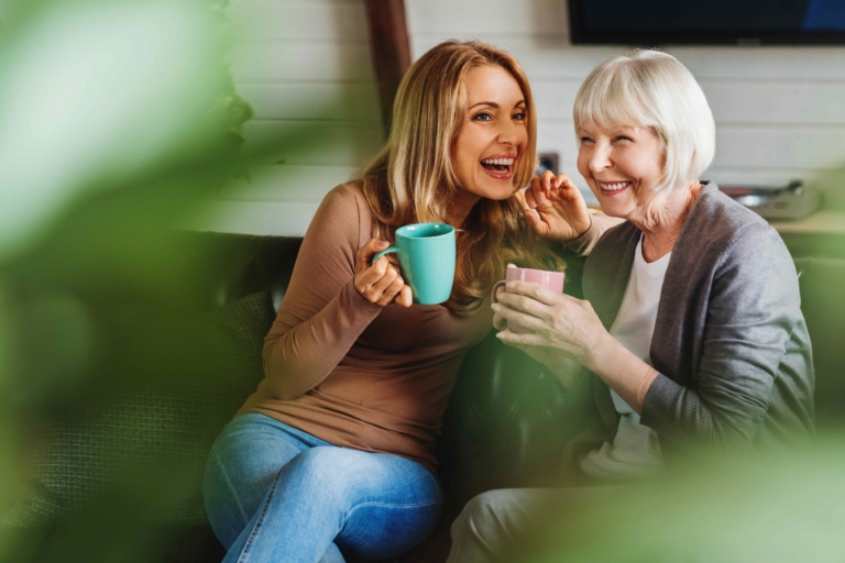 Zwei Frauen unterhalten sich auf dem Sofa und trinken Kaffee